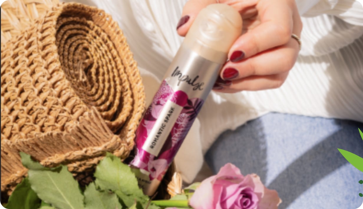 Woman holding a can of Impulse body spray with flowers and a rug next to it